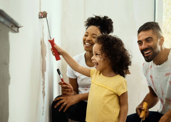 a family of three painting a wall