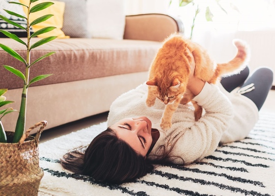 a woman laying on the floor playing with her cat