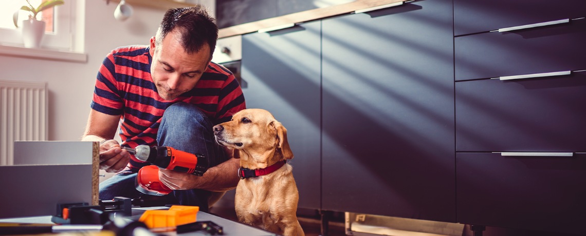 a man holding a tool while his dog watches.